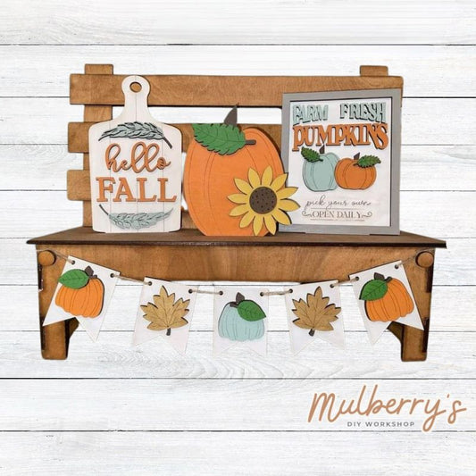 It doesn't get any cuter than our interchangeable bench! It's a perfect add on accessory to your décor. It's approximately 14" tall x 17" wide. Includes: Bench and Fall Inserts. Fall inserts include Farm Fresh Pumpkins sign, Pumpkin, Hello Fall cutting board, and fall banner.