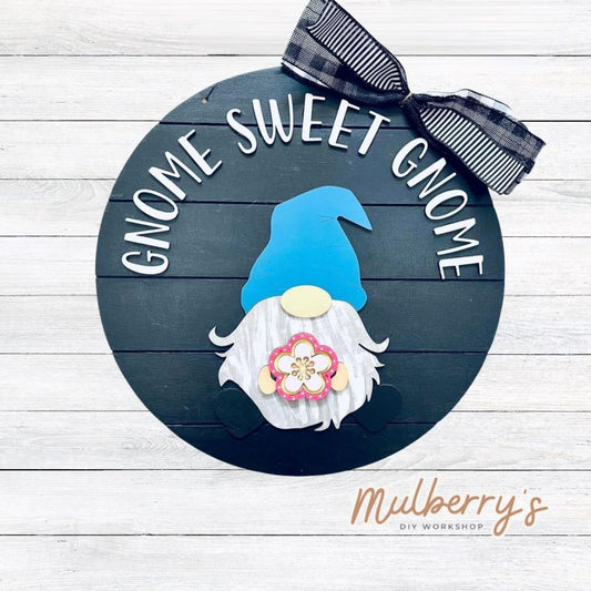 This sweet little fella will make you smile each season and holiday. Simply swap out his hands to create a brand new door hanger! The door hanger is approximately 18-inches in diameter and comes with or without greenery on the backer. Includes Gnome Sweet Gnome door hanger with spring insert.