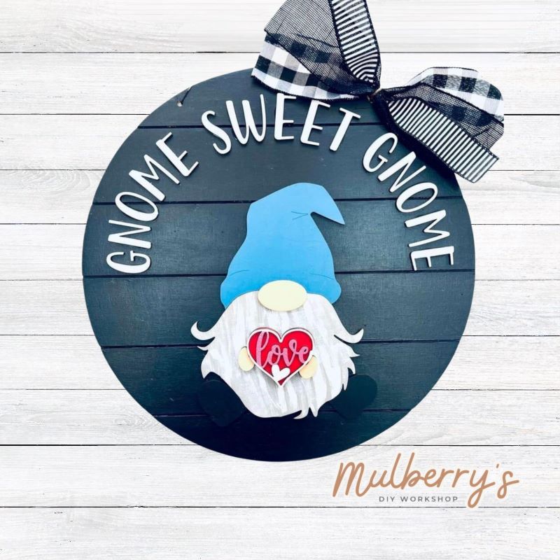 This sweet little fella will make you smile each season and holiday. Simply swap out his hands to create a brand new door hanger! The door hanger is approximately 18-inches in diameter and comes with or without greenery on the backer. Includes Gnome Sweet Gnome door hanger with valentine insert.