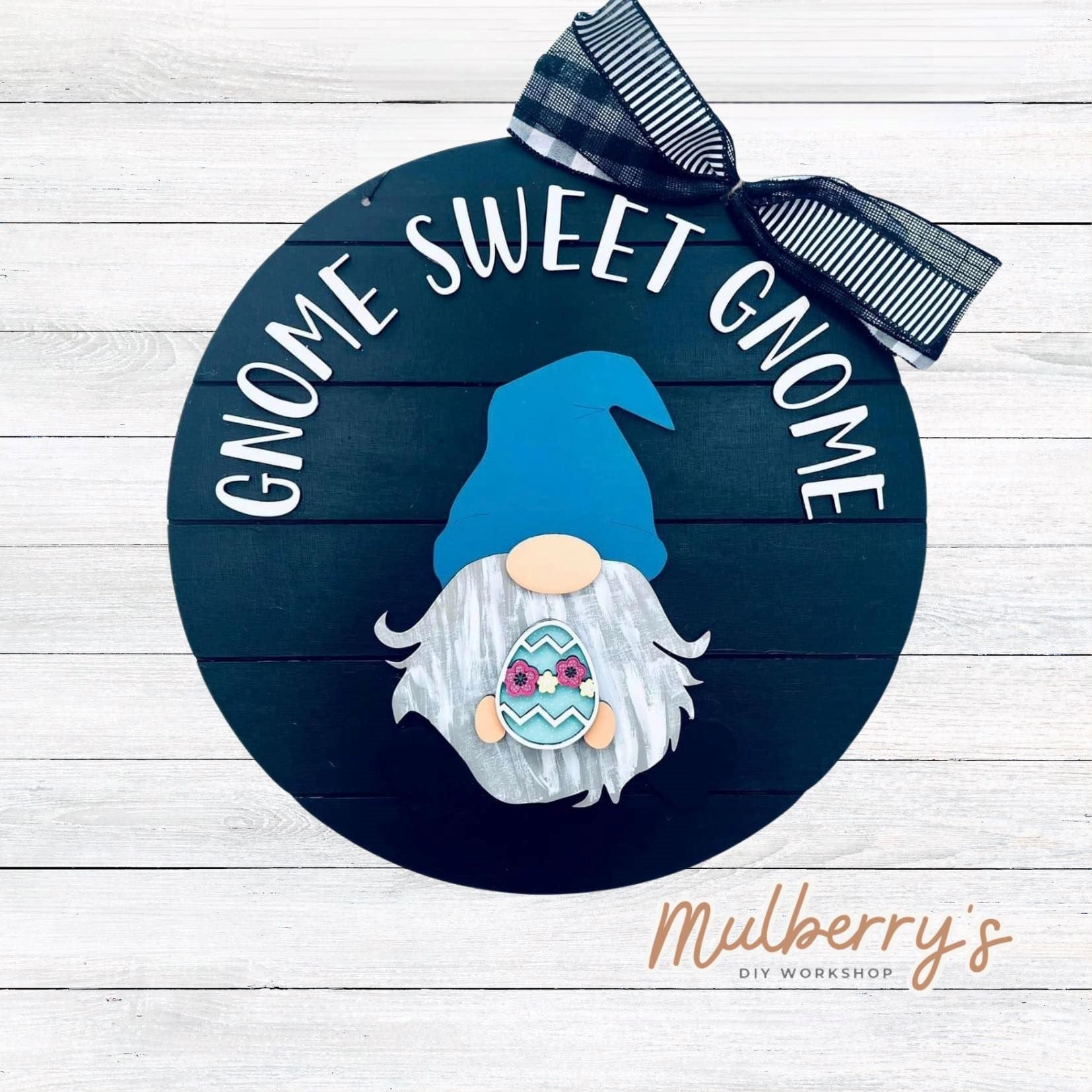 This sweet little fella will make you smile each season and holiday. Simply swap out his hands to create a brand new door hanger. The door hanger is approximately 18-inches in diameter and comes with or without greenery on the backer. Includes Gnome Sweet Gnome door hanger with Easter insert.