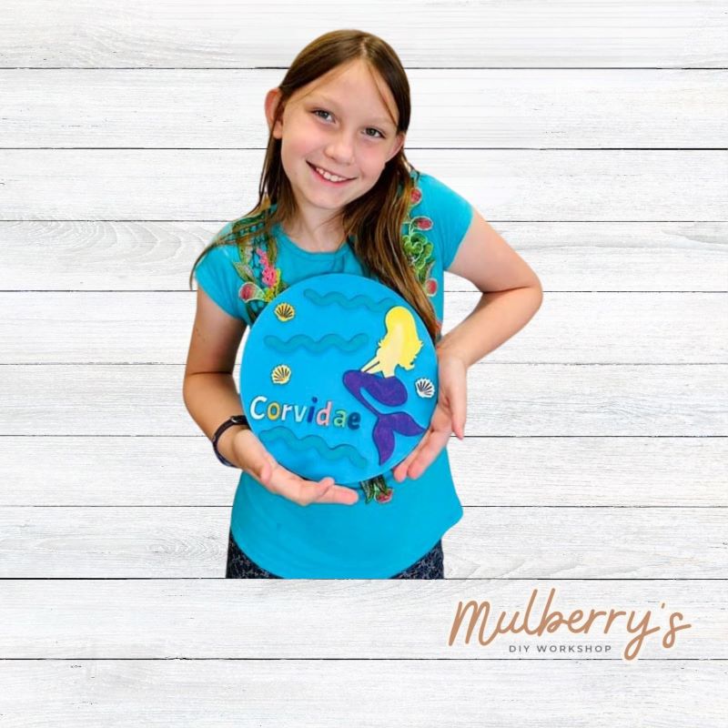 Our mini 9.5" door hanger with a sitting mermaid and is a popular project for kids! This design can be personalized with a name in either print or cursive.