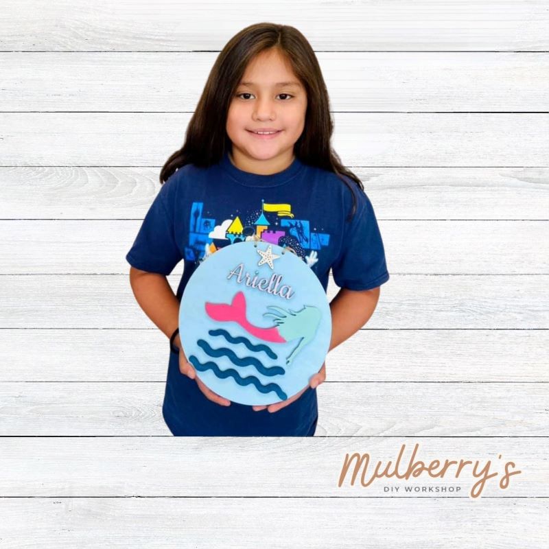 Our mini 9.5" door hanger with a swimming mermaid and is a popular project for kids! This design can be personalized with a name in either print or cursive.