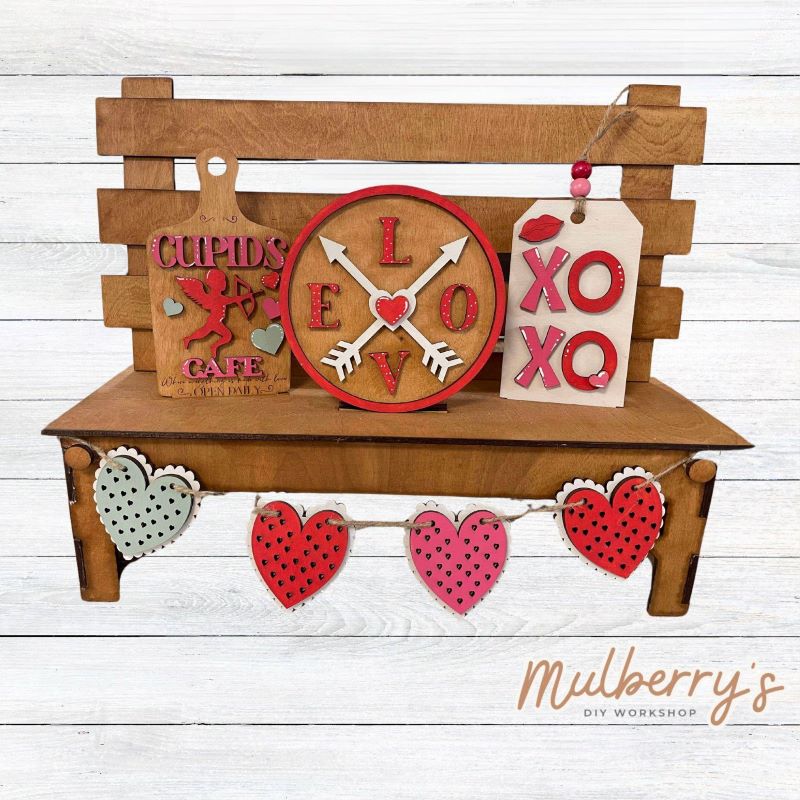 It doesn't get any cuter than our interchangeable bench! It's a perfect add on accessory to your décor. It's approximately 14" tall x 17" wide. Includes: Bench and Valentine Inserts. Valentine inserts include Cupid Cutting Board, LOVE Circle, XOXO Tag, and heart banner.