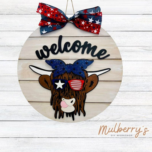 Show off your patriotism with our Welcome Highland Cow 18" door hanger!