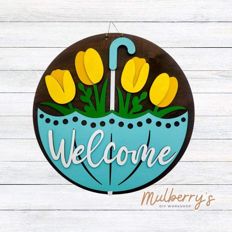 Welcome Spring into your home with this quirky 18 inch door hanger featuring a gigantic umbrella with tulips peeping from the inside.&nbsp; Hang it on your front door to greet guests with a playful touch. Perfect for adding a unique touch to your seasonal decor.