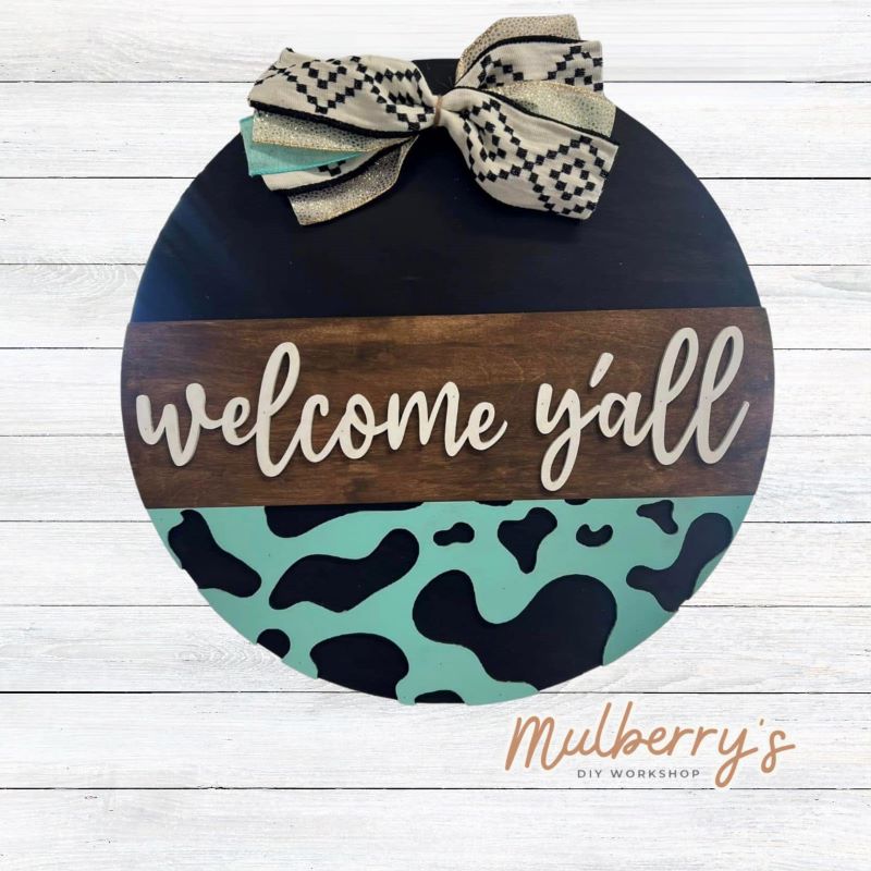 Welcome the cows home with our 18" Welcome Y'all door hanger with cow print design.